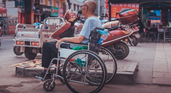 elderly man in a wheelchair on a busy street